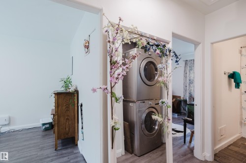 Stacked laundry appliances, wood-finish flooring, white walls, and bright overhead lighting - 11134 11138 116 Street Nw, Edmonton, AB 