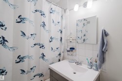 White tile walls, vanity with integrated sink, rectangular mirror, and an overhead light fixture - 