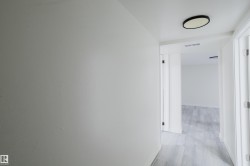 Hallway featuring flush-mount ceiling lighting, crisp white paint, and wood-finish flooring - 