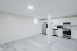 Kitchenette with white cabinetry, stainless steel appliances, white subway tile backsplash, and wood-finish flooring - 