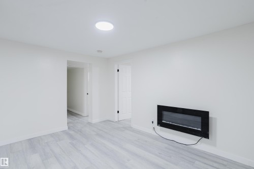 Neutral wall paint, wood-finish flooring, recessed ceiling lighting, and a modern wall-mounted electric fireplace - 11134 11138 116 Street Nw, Edmonton, AB 