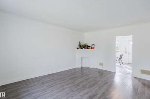 Wood-finish flooring, white painted walls, and a fireplace with a mantel - 11134 11138 116 Street Nw, Edmonton, AB 