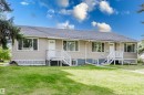 Beige horizontal siding exterior with a dark shingle roof, multiple white-trimmed windows, and two entryways with white staircases - 11134 11138 116 Street Nw, Edmonton, AB 