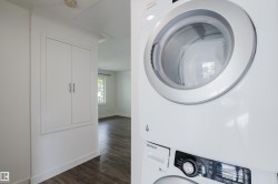 White stacked washer and dryer unit, built-in storage cabinetry, and wood-finish flooring - 