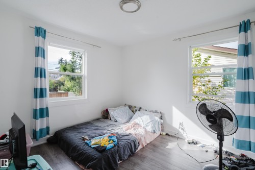 Two windows with white trim, wood-finish flooring, and a flush-mount ceiling light - 11134 11138 116 Street Nw, Edmonton, AB 