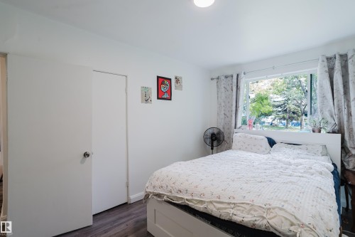Bright interior with wood-finish flooring, white walls, a window featuring a street-facing outlook, and a flush-mount ceiling light - 11134 11138 116 Street Nw, Edmonton, AB 
