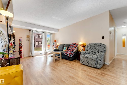 Light wood-finish flooring throughout, bright neutral wall paint, and large sliding glass doors leading to the exterior - #101 49 Akins Dr, St. Albert, AB 