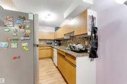 Wood-finish flooring, wood-finish cabinetry, patterned tile backsplash, double basin sink, and recessed lighting - 