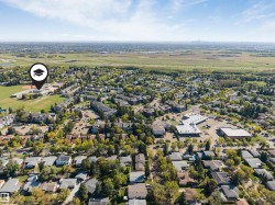 Expansive aerial encompassing a residential area, educational facility with athletic fields, and commercial buildings - 