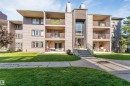 Multi-story building featuring multiple private balconies, a central entrance with large windows, and a paved walkway - #101 49 Akins Dr, St. Albert, AB 