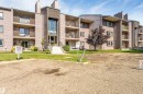 Multi-story building featuring multiple private balconies, light-colored exterior siding, and a prominent central entryway with large windows - #101 49 Akins Dr, St. Albert, AB 