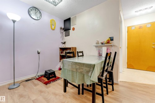 Light wood-finish flooring with a smooth texture, complemented by a yellow entry door and white trim - #101 49 Akins Dr, St. Albert, AB 