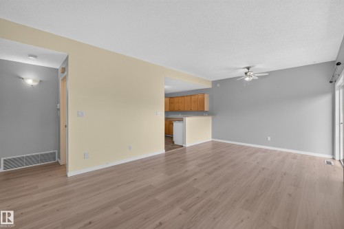 Wood-finish flooring throughout, ceiling fan with light fixture, sliding glass door, and a kitchen featuring wood cabinetry - #156 460 Cranberry Wy, Sherwood Park, AB 