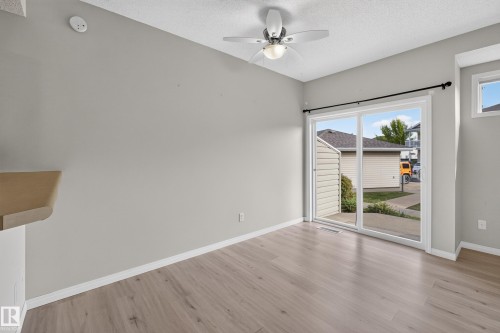 Wood-finish flooring, sliding glass door, overhead lighting with ceiling fan, neutral wall paint, and white trim - #156 460 Cranberry Wy, Sherwood Park, AB 