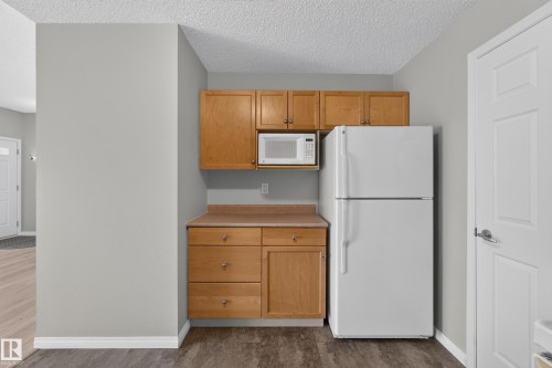 Compact kitchen area featuring wood cabinetry, laminate countertops, and a built-in microwave - #156 460 Cranberry Wy, Sherwood Park, AB 