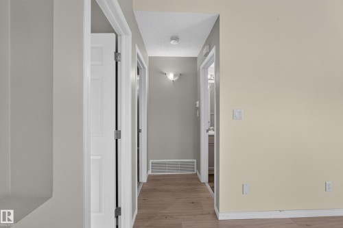 Hallway featuring wood-finish flooring, light neutral paint, and white trim - #156 460 Cranberry Wy, Sherwood Park, AB 