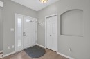 Entryway featuring wood-finish flooring, a white front door with decorative lites, an arched wall niche, and built-in bi-fold closet doors - #156 460 Cranberry Wy, Sherwood Park, AB 