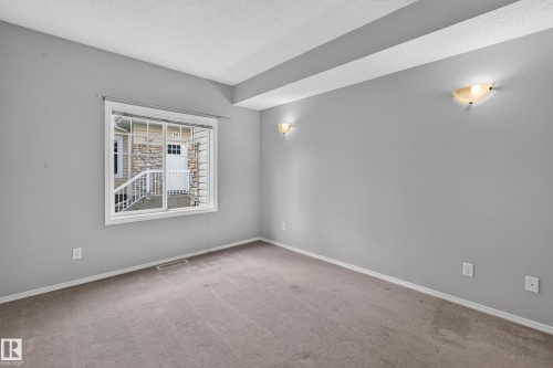 Recessed ceiling detail with integrated lighting, neutral wall paint, broad window with white trim, and wall-mounted sconces - #156 460 Cranberry Wy, Sherwood Park, AB 