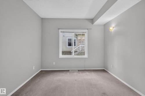 Window with white trim, wall-mounted sconce, and neutral carpeting - #156 460 Cranberry Wy, Sherwood Park, AB 