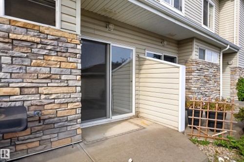 Concrete patio with a sliding glass door and stone facade - #156 460 Cranberry Wy, Sherwood Park, AB 