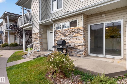 Exterior features include horizontal siding, stone veneer accents, an entry patio, and a ground-level sliding glass door - #156 460 Cranberry Wy, Sherwood Park, AB 