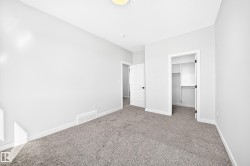 Plush gray carpet, white painted walls, white trim, and a built-in closet with shelving - 