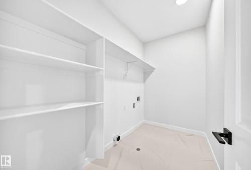 Built-in white shelving, recessed ceiling lighting, tile flooring, and a white interior door with matte black hardware - 19 Tuplet Bay, Spruce Grove, AB 
