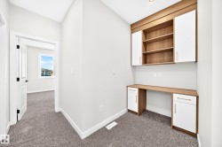 Built-in desk with wood-finish countertop and white cabinetry - 