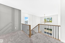 Carpeted landing with decorative wall paneling, a chandelier, and a wood and metal baluster railing - 