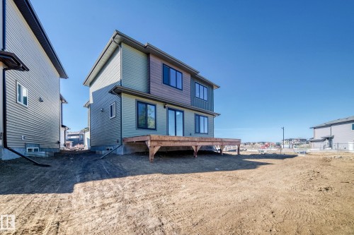 Two-story exterior with multi-toned siding, dark-framed windows, and a large wooden deck - 19 Tuplet Bay, Spruce Grove, AB 