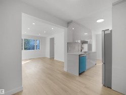 Contemporary kitchen featuring a gray tile backsplash, light gray cabinetry, and a stainless steel refrigerator - 