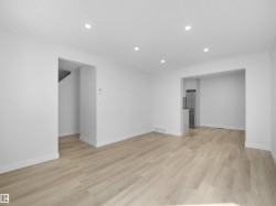 Recessed lighting, light wood-finish flooring, white walls, stainless steel refrigerator, and a built-in kitchen peninsula - 