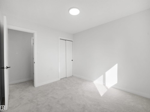 Plush carpeting, white walls, flush-mounted ceiling light fixture, and bifold closet doors with dark hardware - 12C Twin Terrace Nw, Edmonton, AB 