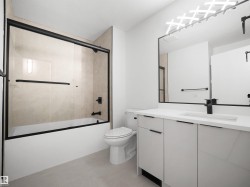 Bathroom featuring a vanity with an integrated sink, black framed mirror, and a tub with a sliding glass door - 