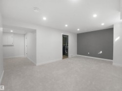Recessed ceiling lighting, light gray carpeting, white walls, and a gray accent wall - 