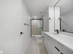 White floating vanity with integrated sink, matte black faucet, frameless mirror, and glass-enclosed shower with black trim - 