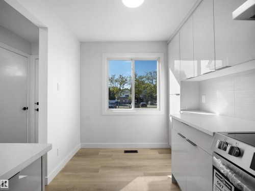 White flat-panel cabinetry with linear pulls, light-toned wood-finish flooring, white countertop, and white subway tile backsplash - 12C Twin Terrace Nw, Edmonton, AB 