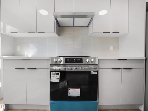 Modern kitchen featuring white flat-panel cabinetry, white tile backsplash, a stainless steel range, and a matching stainless steel range hood - 12C Twin Terrace Nw, Edmonton, AB 