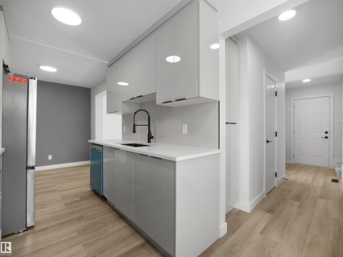 Contemporary kitchen featuring sleek gray cabinetry, a black gooseneck faucet, light countertops, subway tile backsplash, and recessed lighting - 12C Twin Terrace Nw, Edmonton, AB 