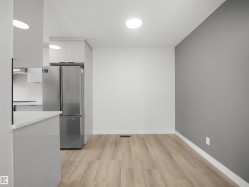 Wood-finish flooring with white baseboards, recessed lighting, and a stainless steel refrigerator - 