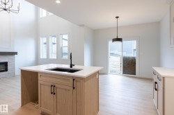 Kitchen island with light wood-finish cabinetry, white countertop, and integrated black sink - 