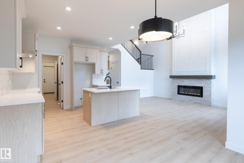 Kitchen featuring white shaker cabinetry, an island with an undermount sink, and light wood-finish flooring - 4005 36 Street, Beaumont, AB 
