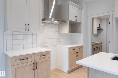 Two-tone cabinetry, stainless steel range hood, white square tile backsplash, white countertops, and wood-finish flooring - 4005 36 Street, Beaumont, AB 