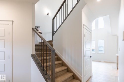 Carpeted staircase with dark wood-finish handrails and black metal balusters - 4005 36 Street, Beaumont, AB 