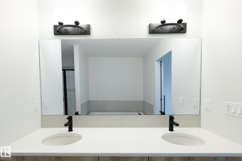 Dual vanity with integrated sinks, light-toned countertop, and dark-finish wall-mounted fixtures - 4005 36 Street, Beaumont, AB 