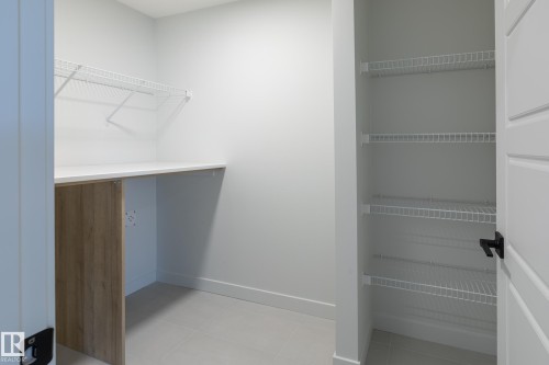 Built-in countertop with wood-finish paneling, white wire shelving, and light-toned floor tiles - 4005 36 Street, Beaumont, AB 