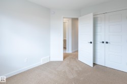 Light-colored carpeting with white trim, modern white doors with matte black hardware, and an adjoining space with recessed lighting - 