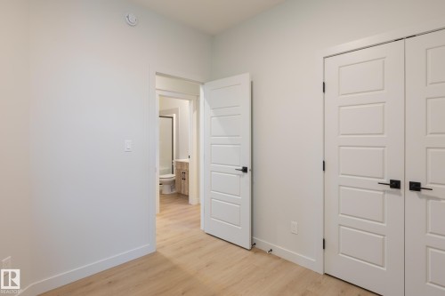 Light wood-finish flooring, white walls, and modern paneled doors with black hardware - 4005 36 Street, Beaumont, AB 