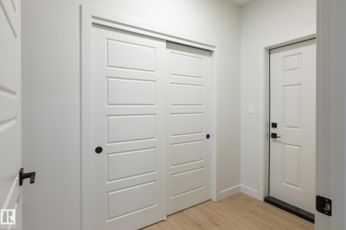 Light wood-finish flooring, white walls, and modern white interior doors with black hardware - 4005 36 Street, Beaumont, AB 