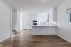 Open-concept kitchen with white cabinetry and appliances, wood-finish flooring, and recessed lighting - 